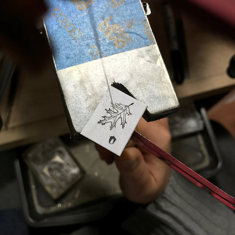 Hand sawing through recycled sterling silver oak leaf and acorn Planting the Future pendant by Beth Millner Jewelry