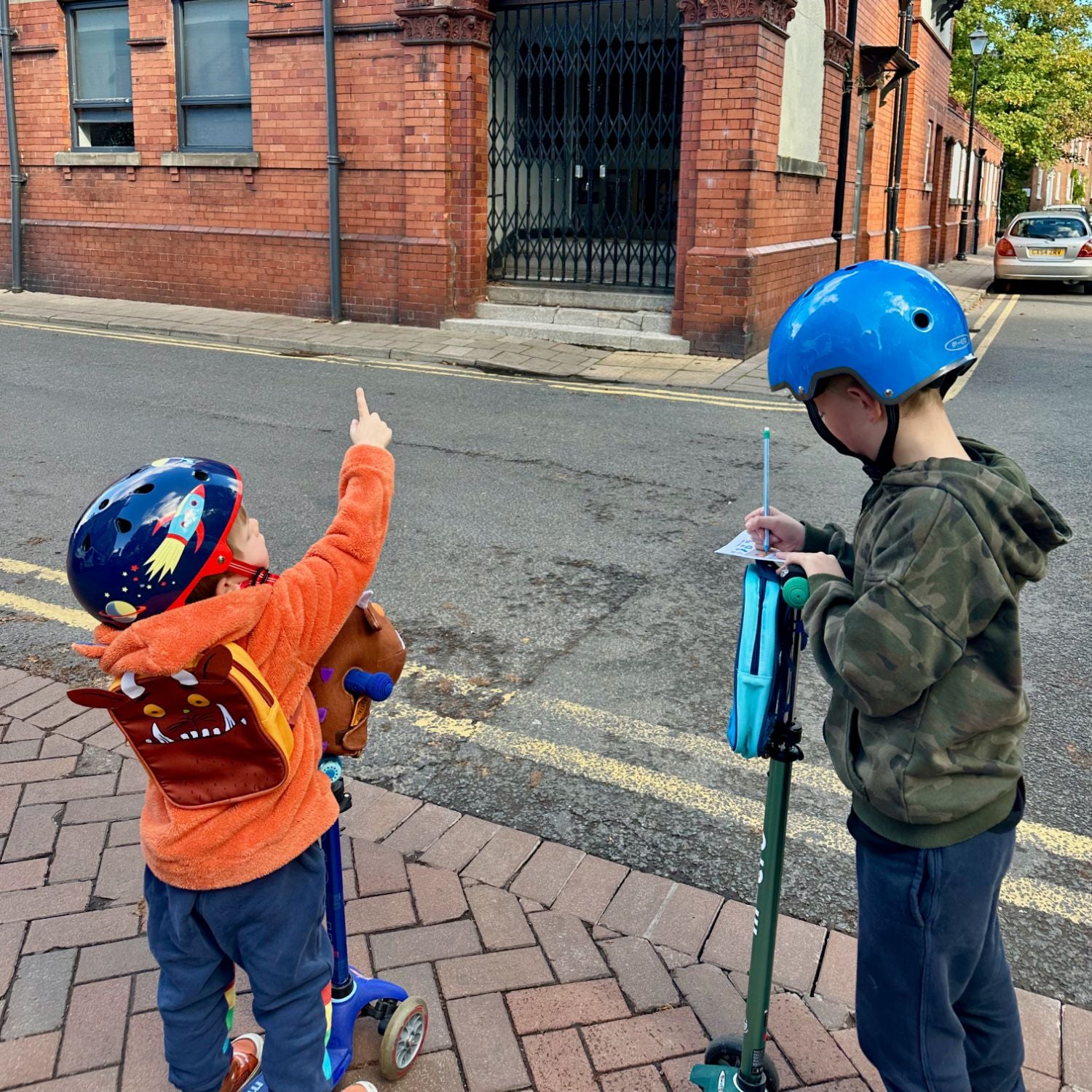 Two children out and about solving clues on their Trail while using their Micro Scooters