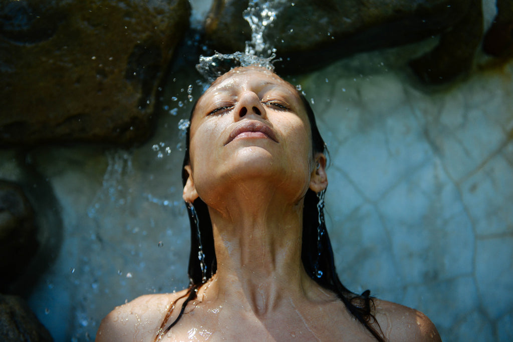 woman bathing under water stream