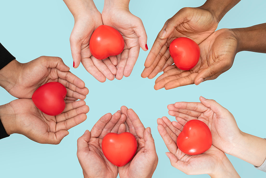 five hands holding heart-shaped tomatoes