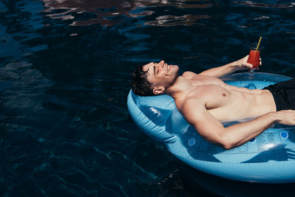 young man lying down on water with pool ring
