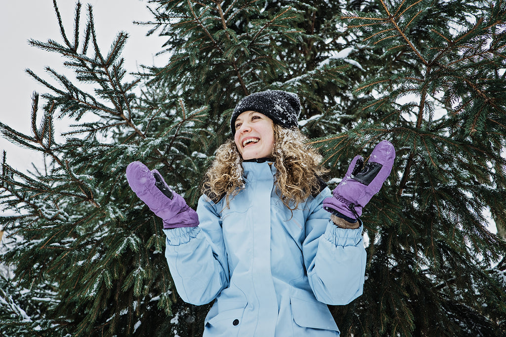 young woman outdoors in winter playing ith snow