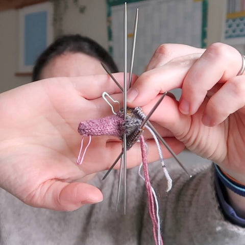 The host of the Eldenwood Craft podcast shows the start of a new knitting project. It's difficult to tell what it will be as it has only just been started but what is being shown is in fact the beak of a duck. 