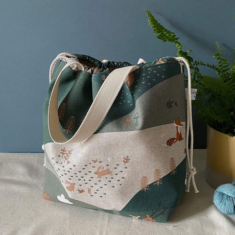 Extra large knitting project bag in a fabric featuring green fields and cute animals. Handmade in Somerset by Eldenwood Craft.