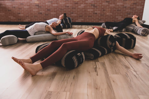 WOman doing fish pose on zabuton mat with multiple bolster cushions