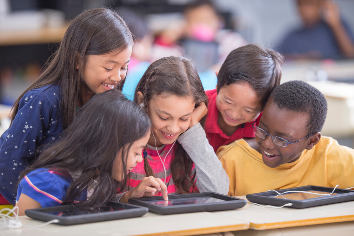 Small group of school kids learning and interacting on tablets