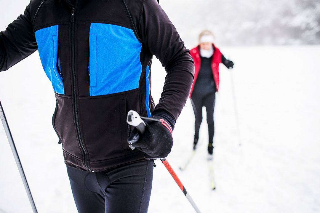 le torse d'un skieur de fond et de sa conjointe quelque pas derrière lui