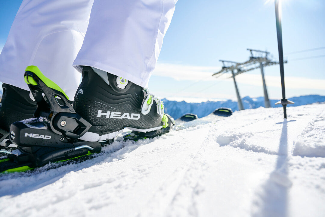 plan rapproché des bottes de ski alpin de la marque HEAD rentrées dans les skis alpins garées sur une piste de montagne, prêt pour le ski haute route