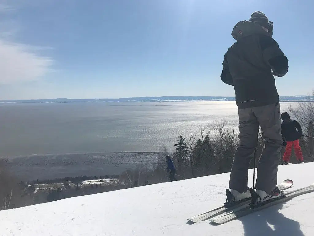 Un skieur au Massif de Charlevoix avec la vue du fleuve St-Laurent.