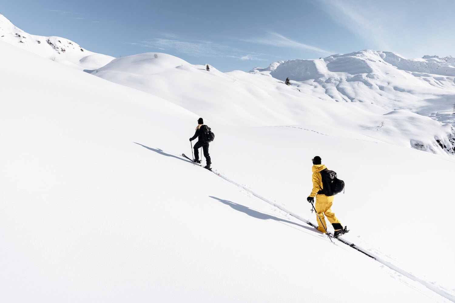 Deux skieurs en backcountry montant une montagne complètement enneigée