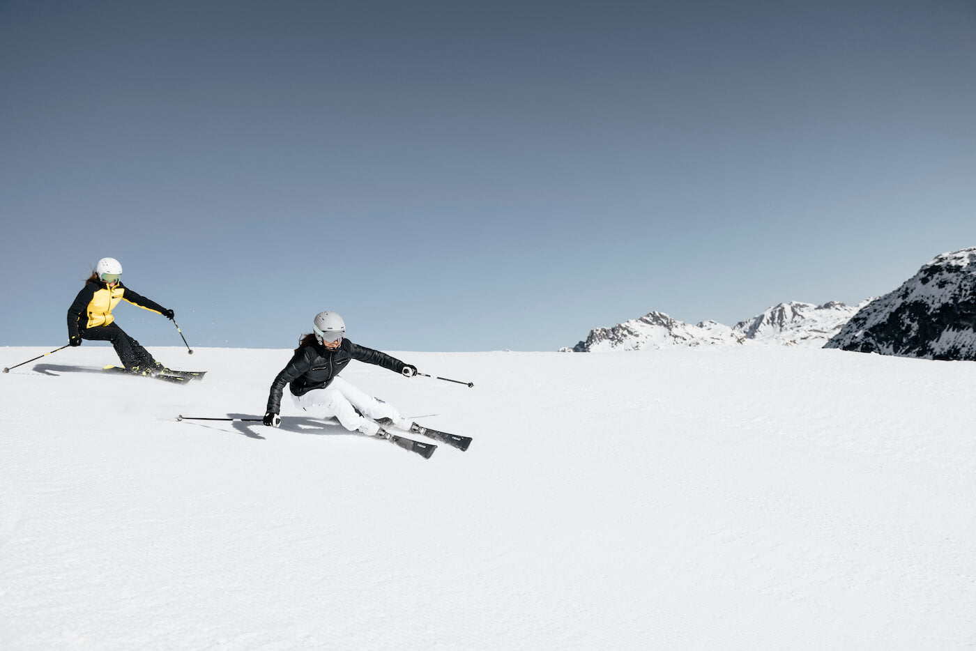 Deux skieurs de piste se suivant en ligne sur une descente en montagne