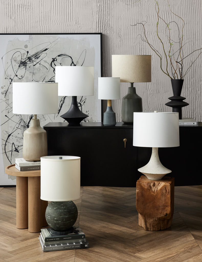Six ceramic table lamps sit on a sideboard and two short side tables. The lamsp all have linen shades.