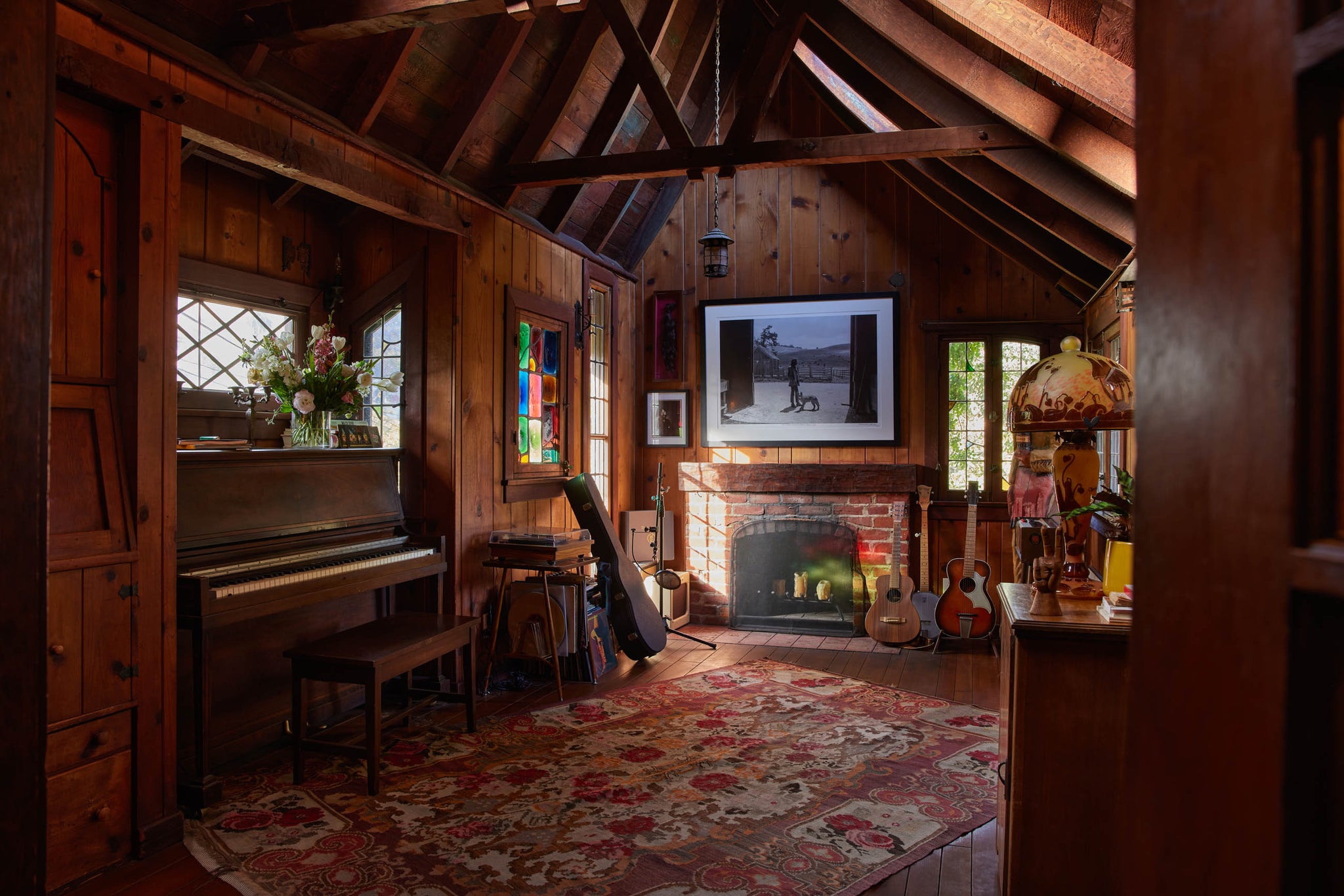 Chase Cohl's music room has a vaulted ceiling and wood paneled walls and ceiling. A piano and four guitars line the room.