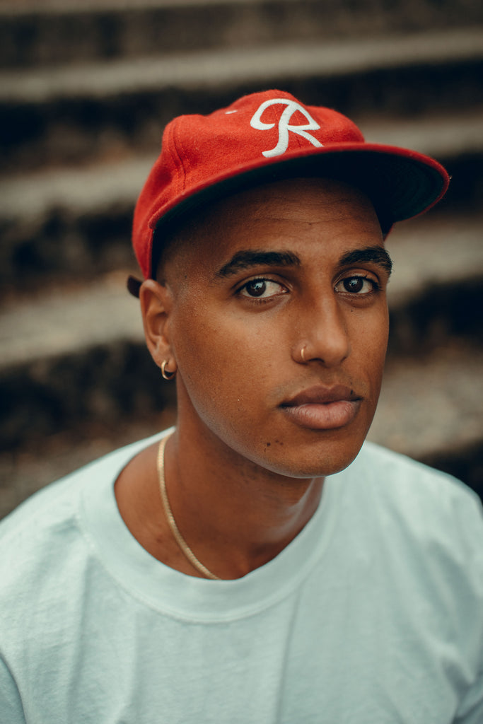 Multidisciplinary artist Adrian Brandon wears a red baseball cap and light green shirt.