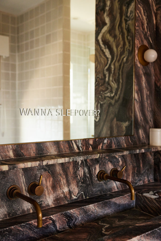 Bathroom mirror featuring a sign saying "Wanna Sleepover?"