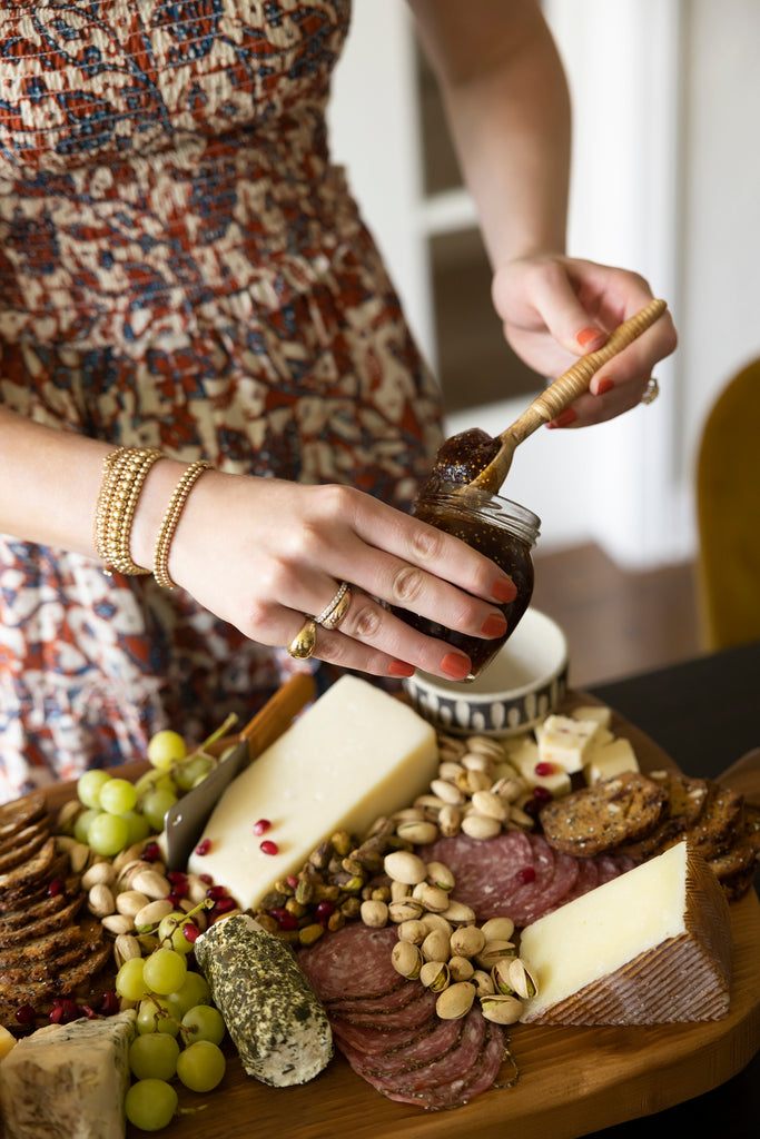 Interior designer Lexie Layne Sokolow scoops jam out of a jar for a charcuterie board with meats, cheeses and nuts.