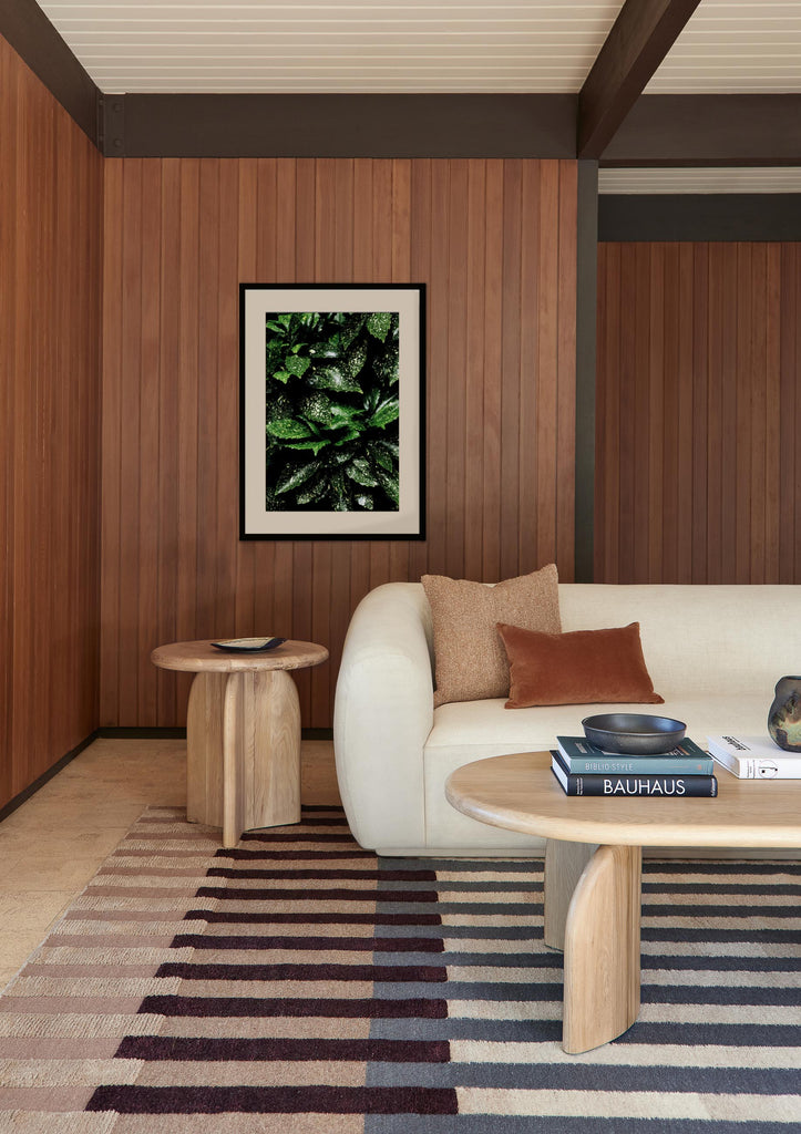 A black and green leaf photography print by Ashley Johnson hangs in a mid-century living room.