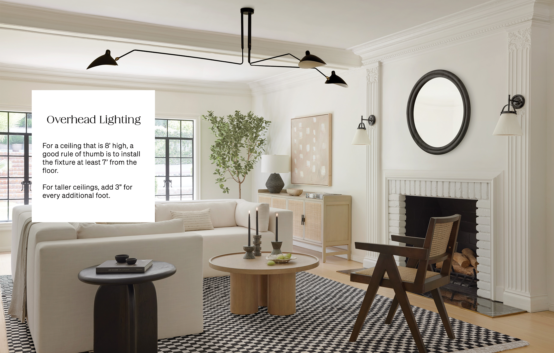 A modern black large chandelier hangs over a light living room with a white sectional sofa, round light wood coffee table, and dark wood and rattan accent chair atop a white and black checkerboard rug