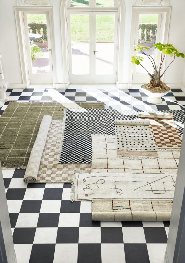 Area rugs from the Sarah Sherman Samuel and Lulu and Georgia collection are layered on a black and white checkered floor.