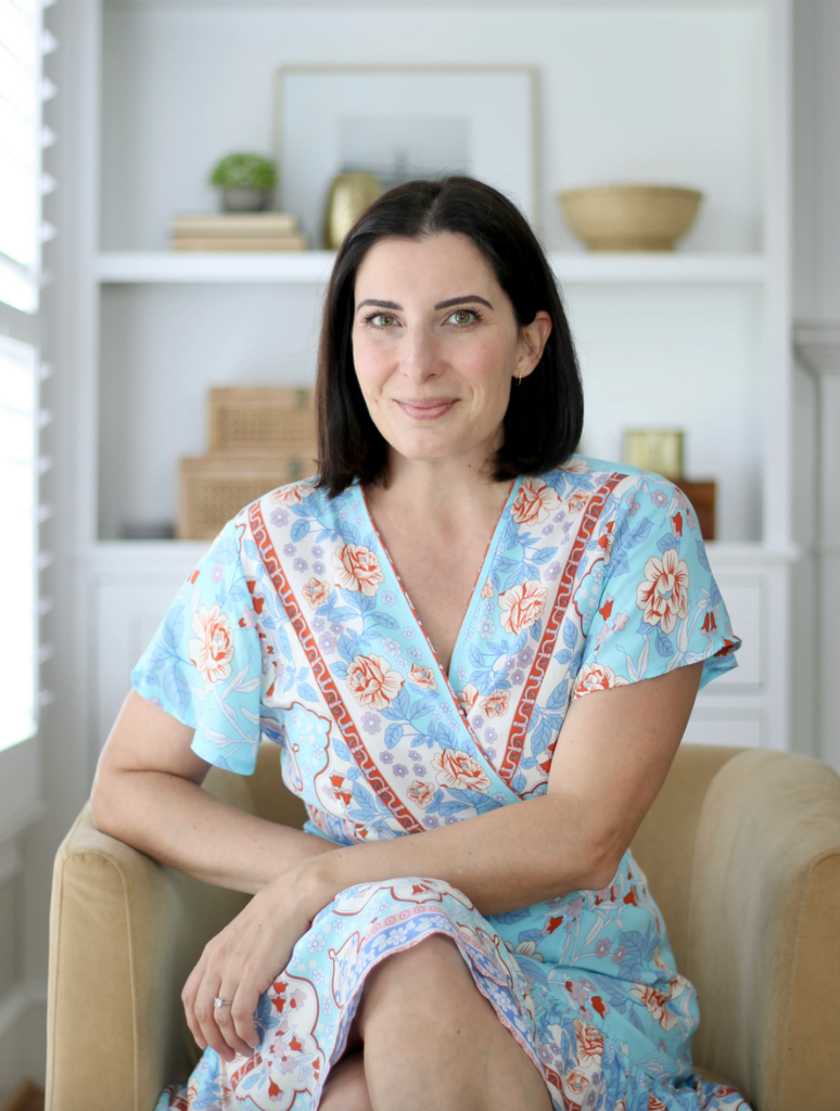 Interior designer and blogger Stefana Silber sits in her Maryland home wearing a blue and red dress.