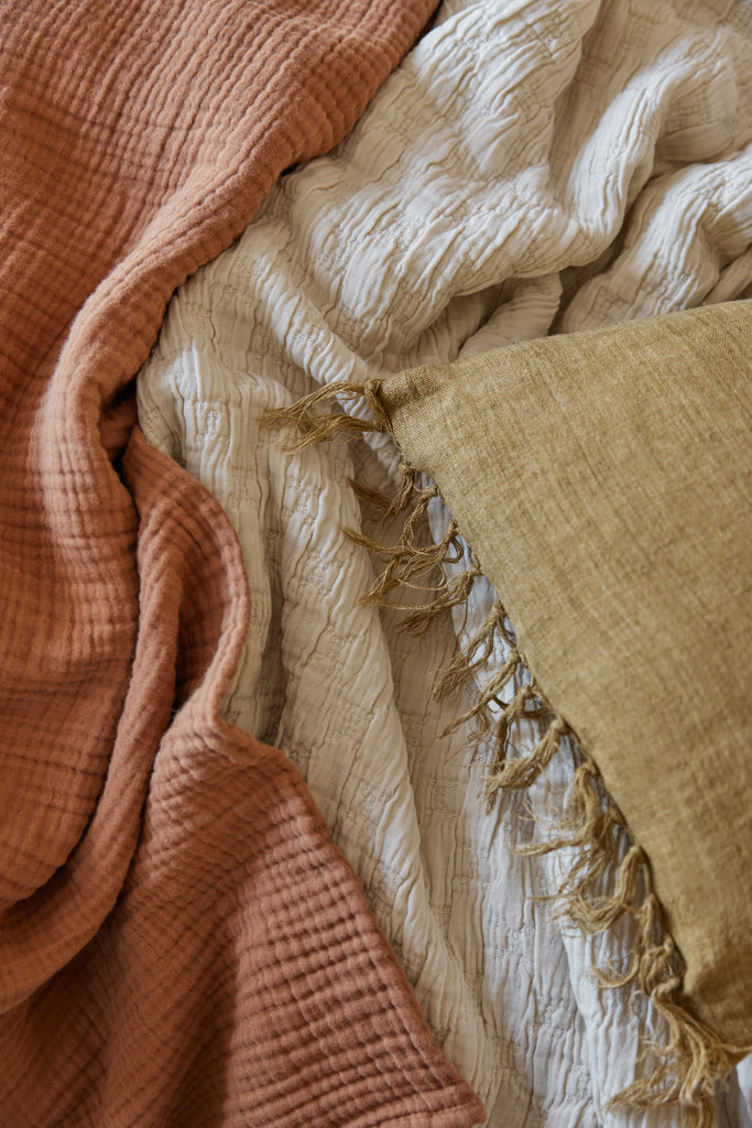 Rust orange, beige, and mustard yellow linen fabrics are layered together.