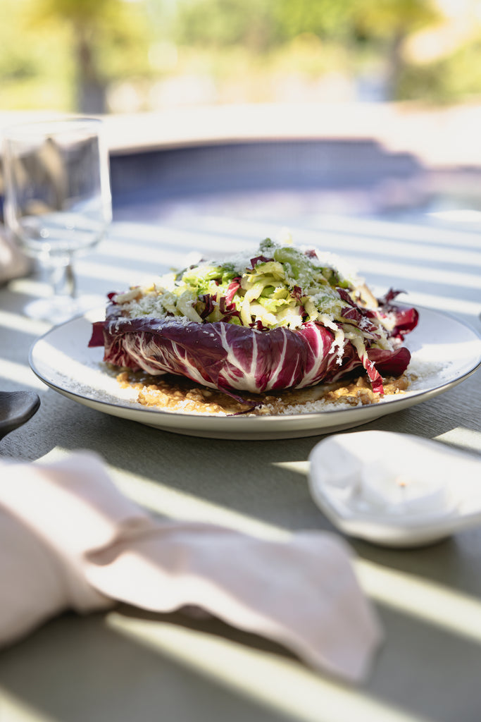 A plate of fall pesto salad sits on a white plate with black rim.