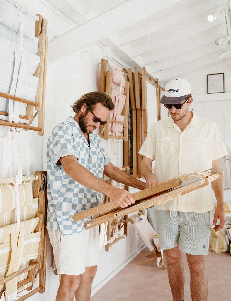 Business & Pleasure Co. founders Ollie Edwards and Lachlan Leckie examine one of their teak beach chairs.