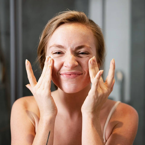 Жена слага крем на лицето си