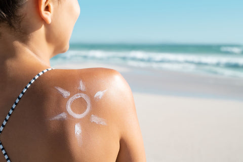Жена на плаж с крем във формата на слънце на рамото