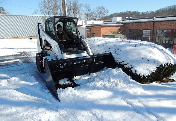 bobcat clearing snow with snow bucket