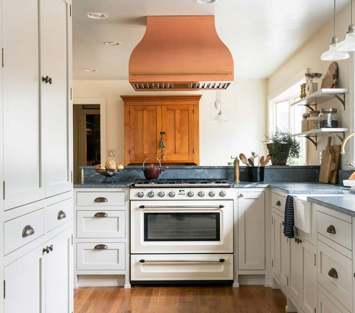 Country kitchen with white cabinets, blue countertop and antique silver cup pulls. The Modern white range has a copper hood vent. 