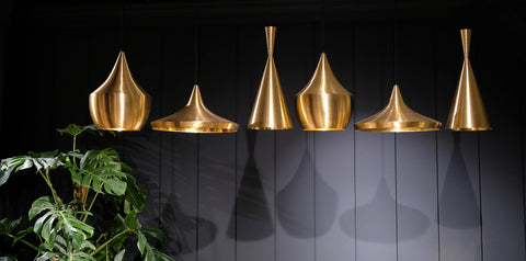 brass hanging lights against a black wall