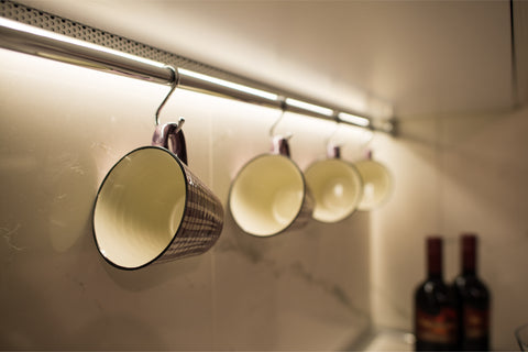 coffee cups hanging from a metal rod under a kitchen cabinet