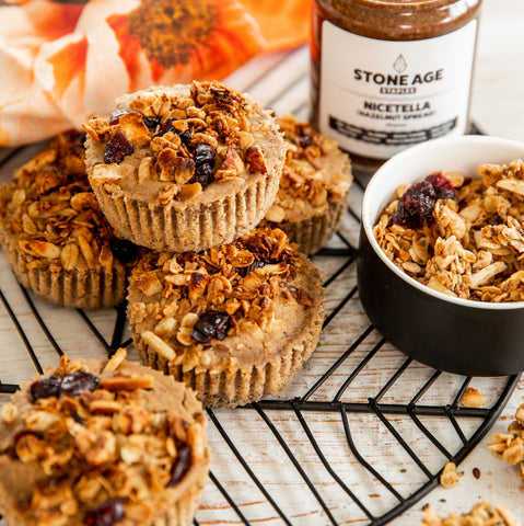 Muffins on a baking tray with jar of Nicetella and small bowl of granola in the background