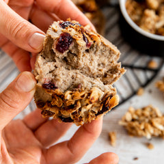 Close up of lady holding muffin and breaking in half to show inside 