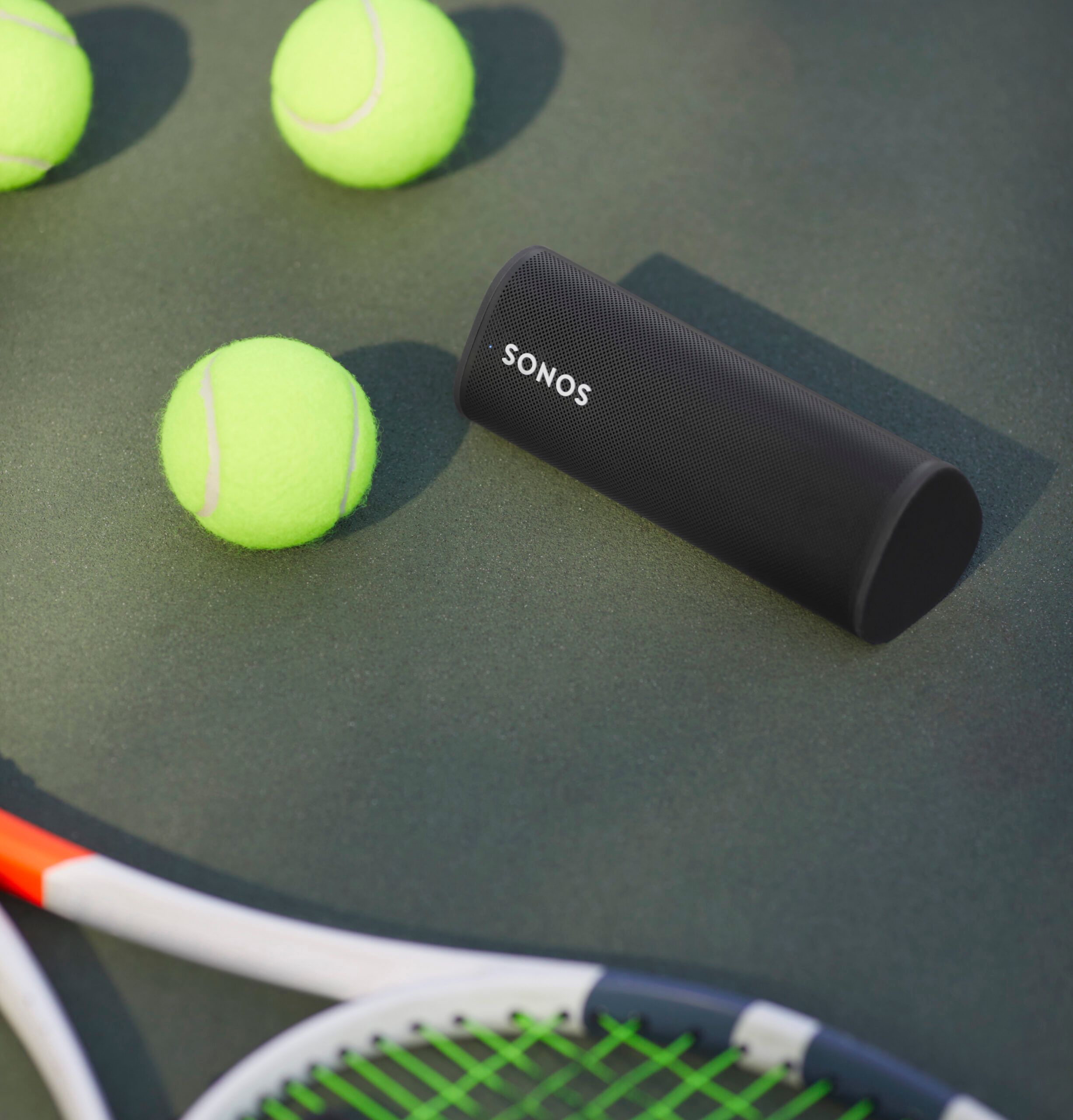 Sonos Roam next to tennis racket and tennis balls