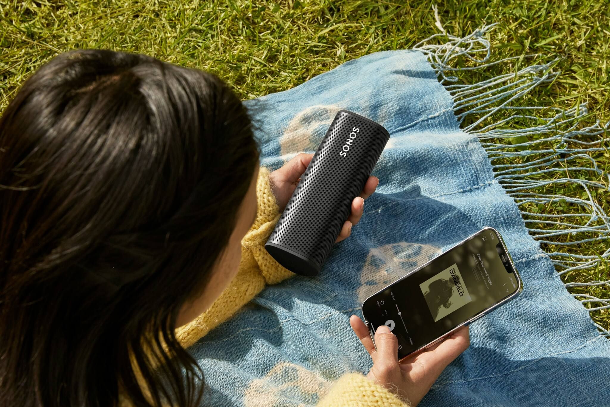 Choosing songs on a picnic with black Sonos Roam