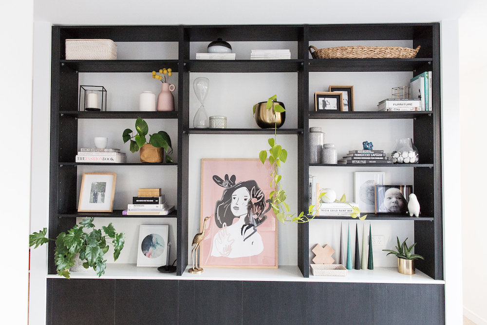 Black minimalist bookshelf with plants and paintings