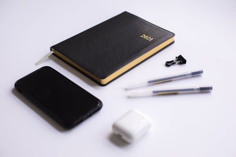 layout of essential stuff - journal, pen, earbuds, phone