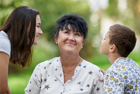 Una madre entre sus dos hijos luciendo feliz - The Happiness Box