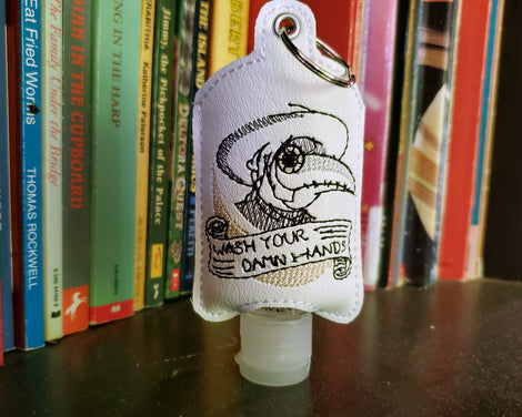 A vinyl hand santizer holder with the plague doctor and Wash Your Damn Hands!