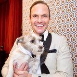 Jason Mitchell Kahn holding his dog wearing a white tuxedo top with black trim.
