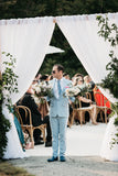 Jason Mitchell Kahn holding flowers dressed in a light blue suit