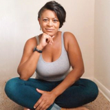Black woman sitting with legs crossed and hand to chin