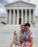 The Ariels - two women with short hair in front of a columned building - both wearing tie dye