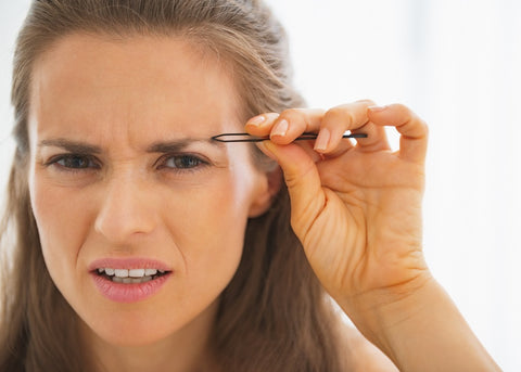 Woman / bride tweezing her eyebrows