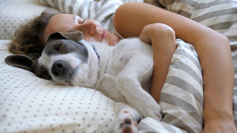 Woman sleeping with her dog; good sleep habits