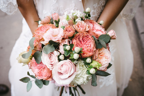 Bride on her wedding day holding a modern bridal bouquet with peach and pink flowers