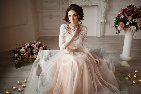 Bride sitting down wearing a blush colored two-piece wedding dress