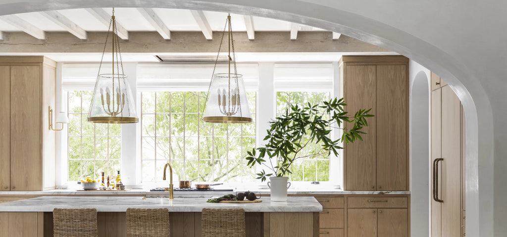 Cocina con amplias ventanas y muebles minimalistas, iluminada por lámparas de techo modernas y geométricas de la marca Visual Comfort